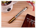 Gold and silver metallic marker pen set with dual tips lying on a white surface