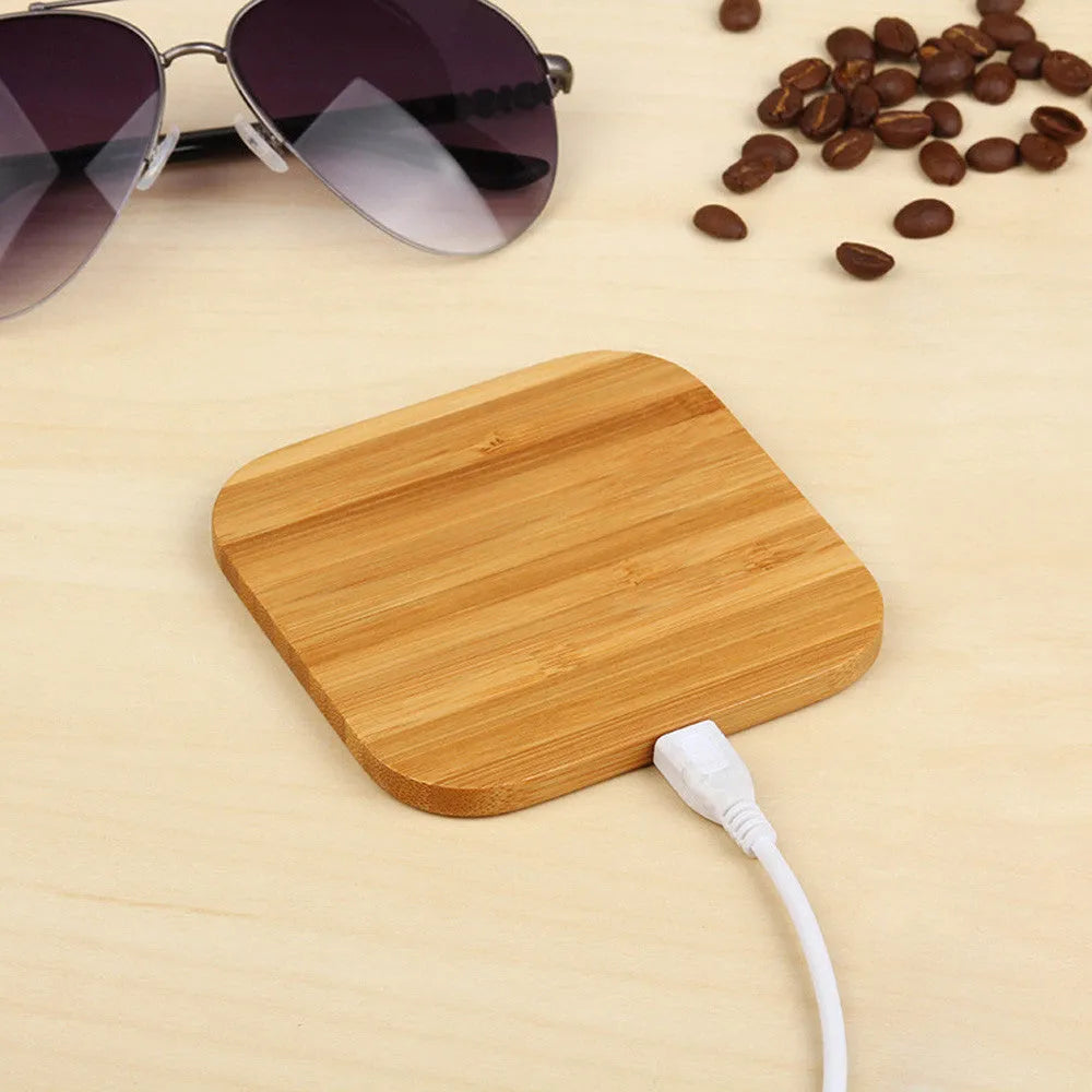 Square natural bamboo 5W QI wireless charging pad on a wooden surface.