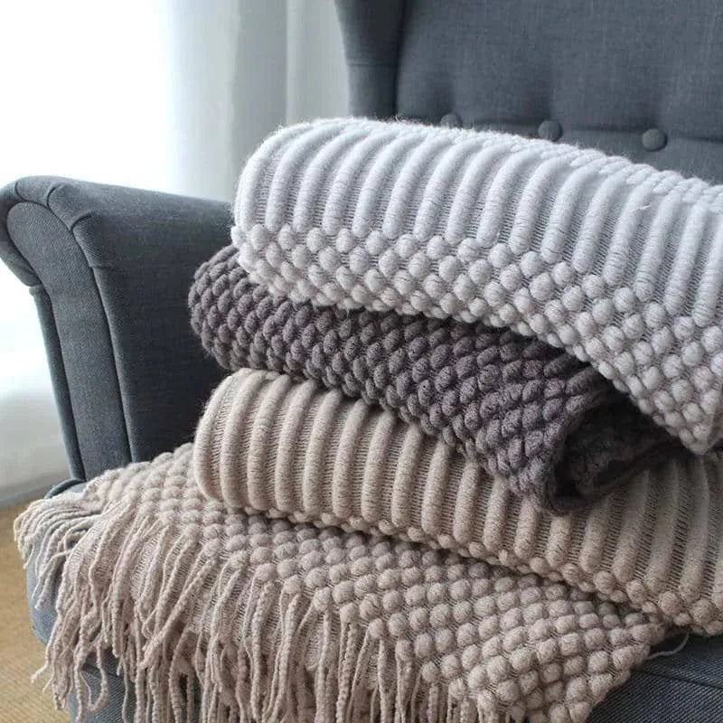 Small light grey polyester fleece throw blanket folded on a sofa.