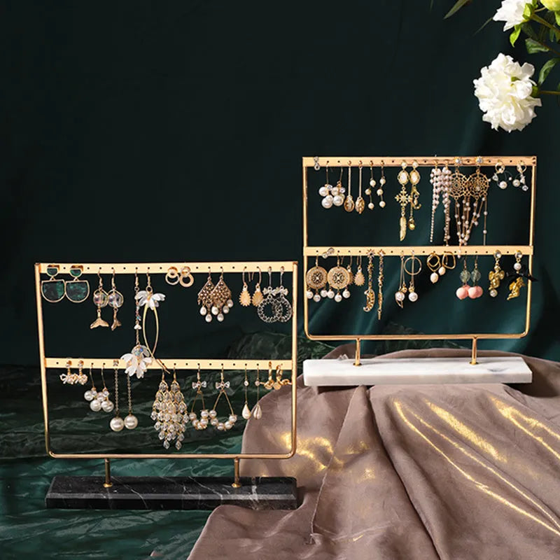 Alloy earring storage rack in green holding stud and drop earrings on a desktop