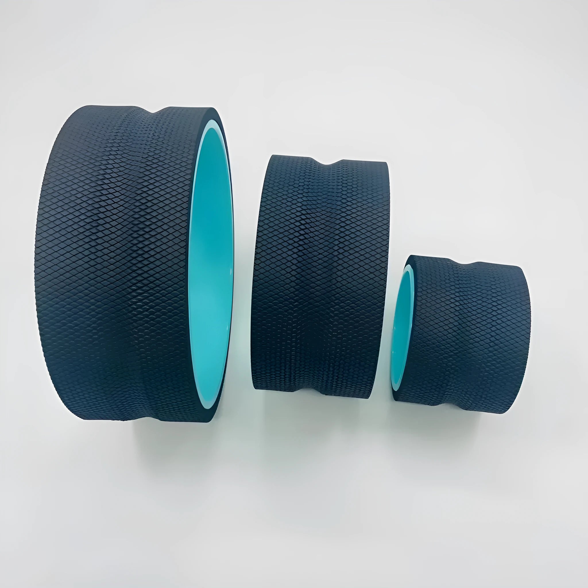 Black yoga wheel four-piece set with foam roller, Pilates ring, and stretching strap on a floor