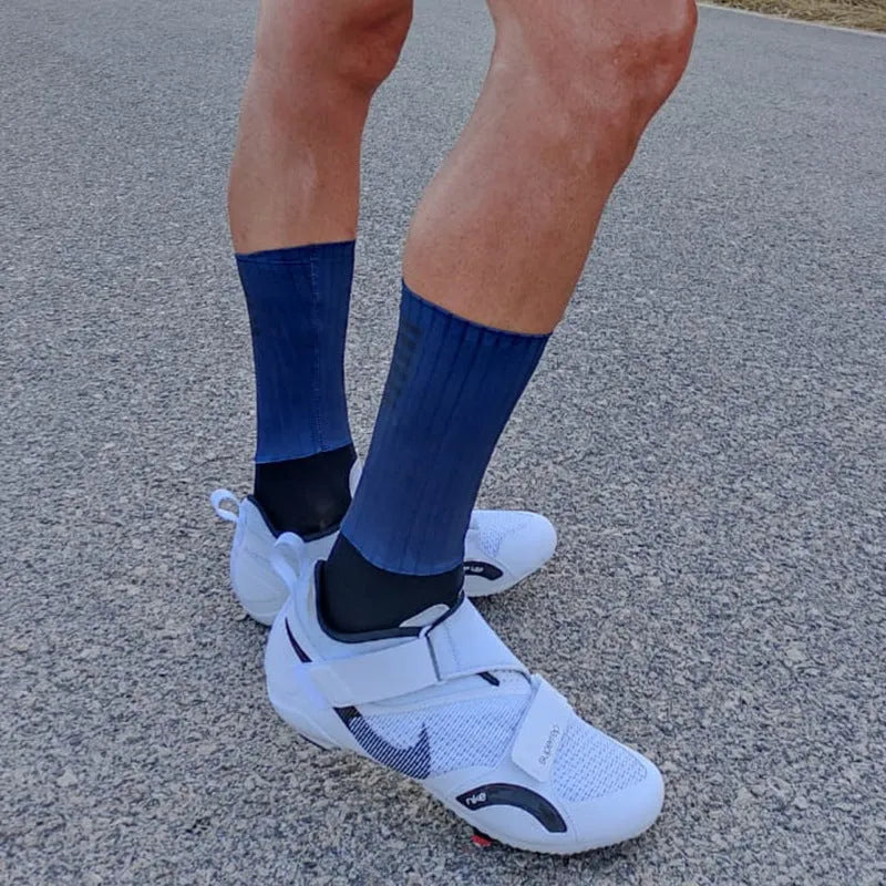 Cycling and running socks in chemical fibre blend fabric shown in orange, black, purple, white, grey, and dark blue colours.