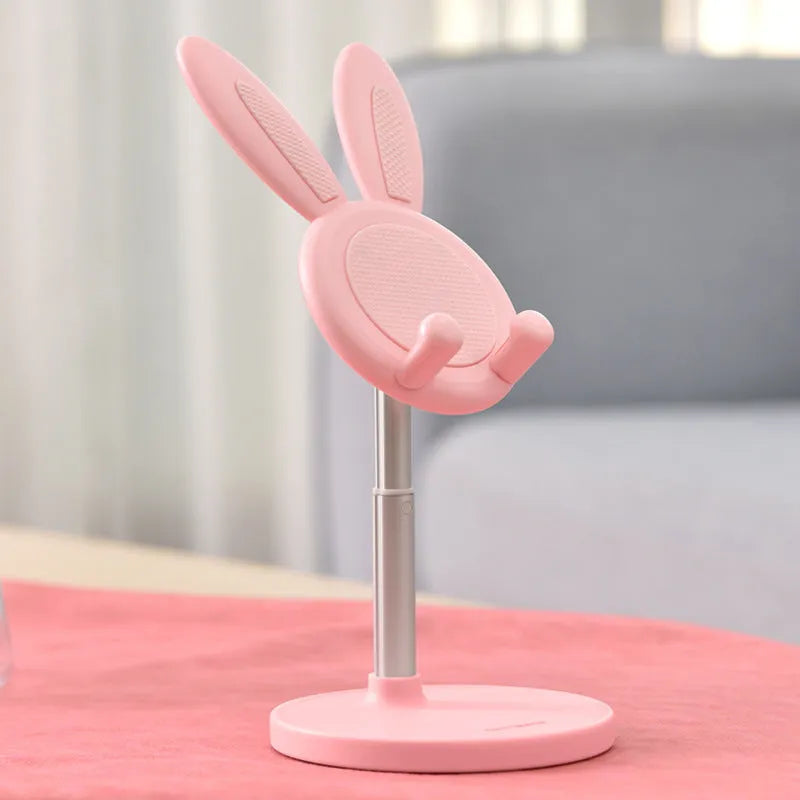 Rabbit-shaped silicone phone stand in pink on a desk with a smartphone placed in it