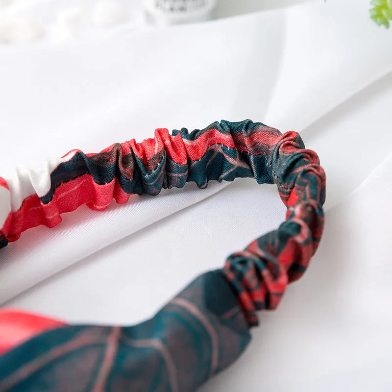 Red cloth headband for women with a banana leaf and cross pattern, showing elastic band.