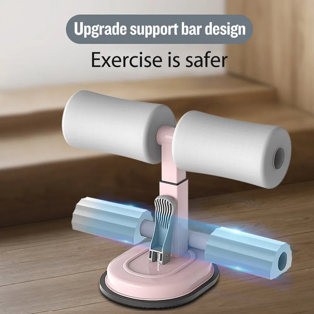 Pink adjustable sit-up bar with foam handles and suction base on a smooth floor for home fitness
