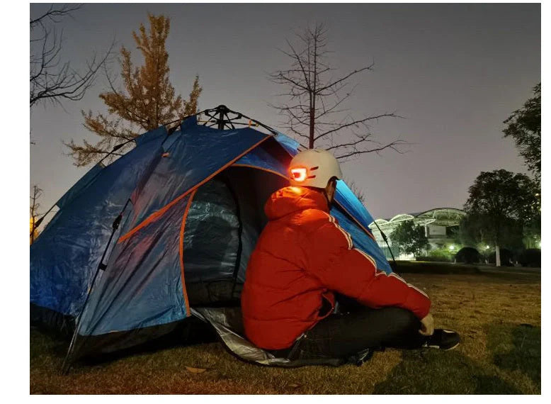 Black cycling helmet with built-in LED headlight and taillight showing adjustable dial and ventilation ports