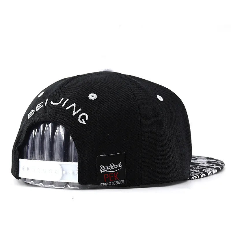 Black and white cotton baseball cap with letter embroidery on the front, showing adjustable strap at back.