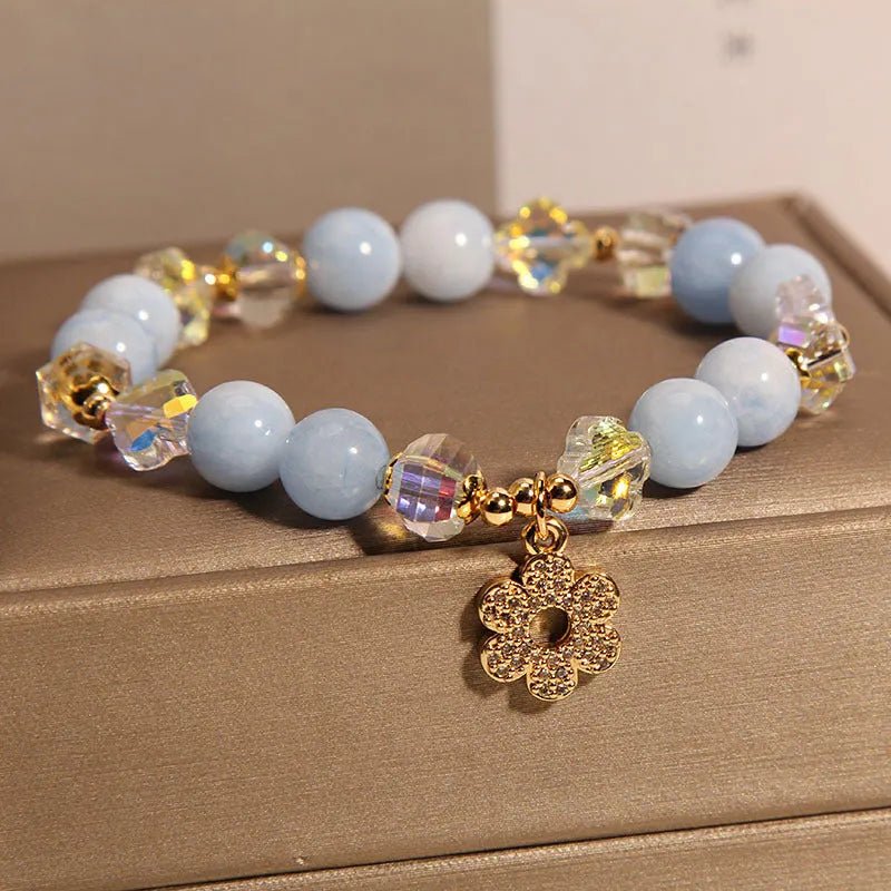 Women's aquamarine crystal bracelet with a four-leaf clover charm and small pearl accent.