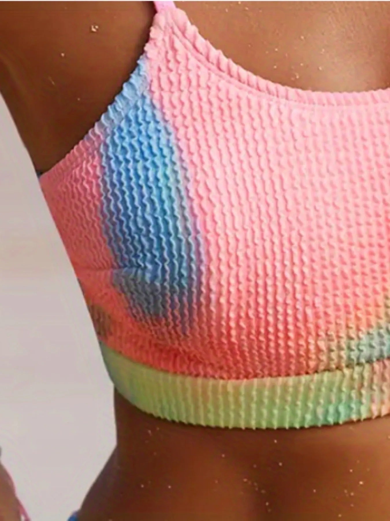 Women's blue and orange tie-dye pleated split bikini on a mannequin, showing gradient pattern and briefs style.