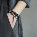 Ethnic style black hair bracelet with white crystal tassel showing bending and lacing construction details