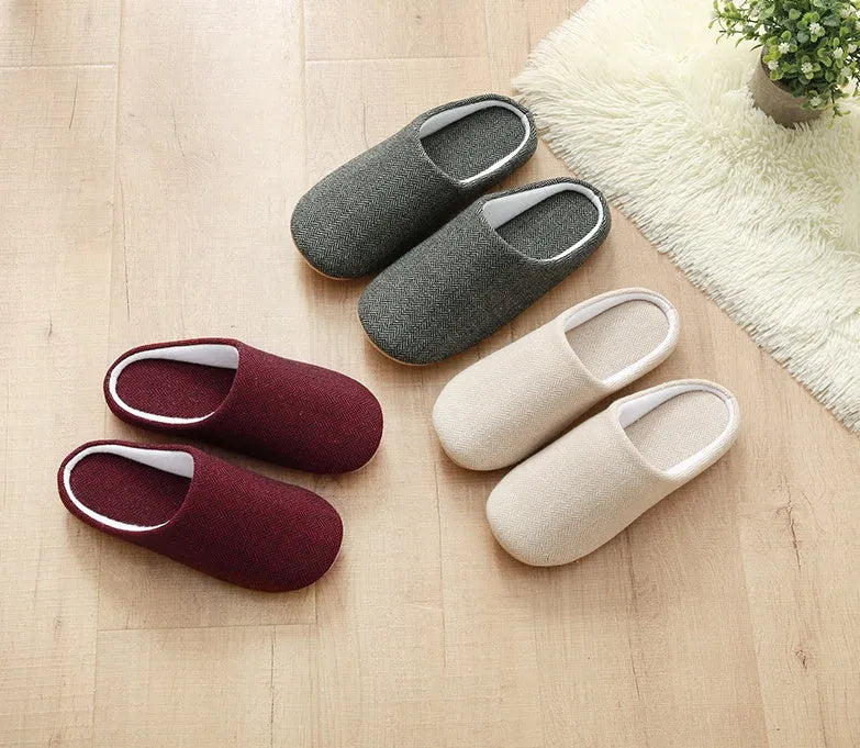 Men's black cotton indoor slippers with soft anti-skid sole on a wooden floor