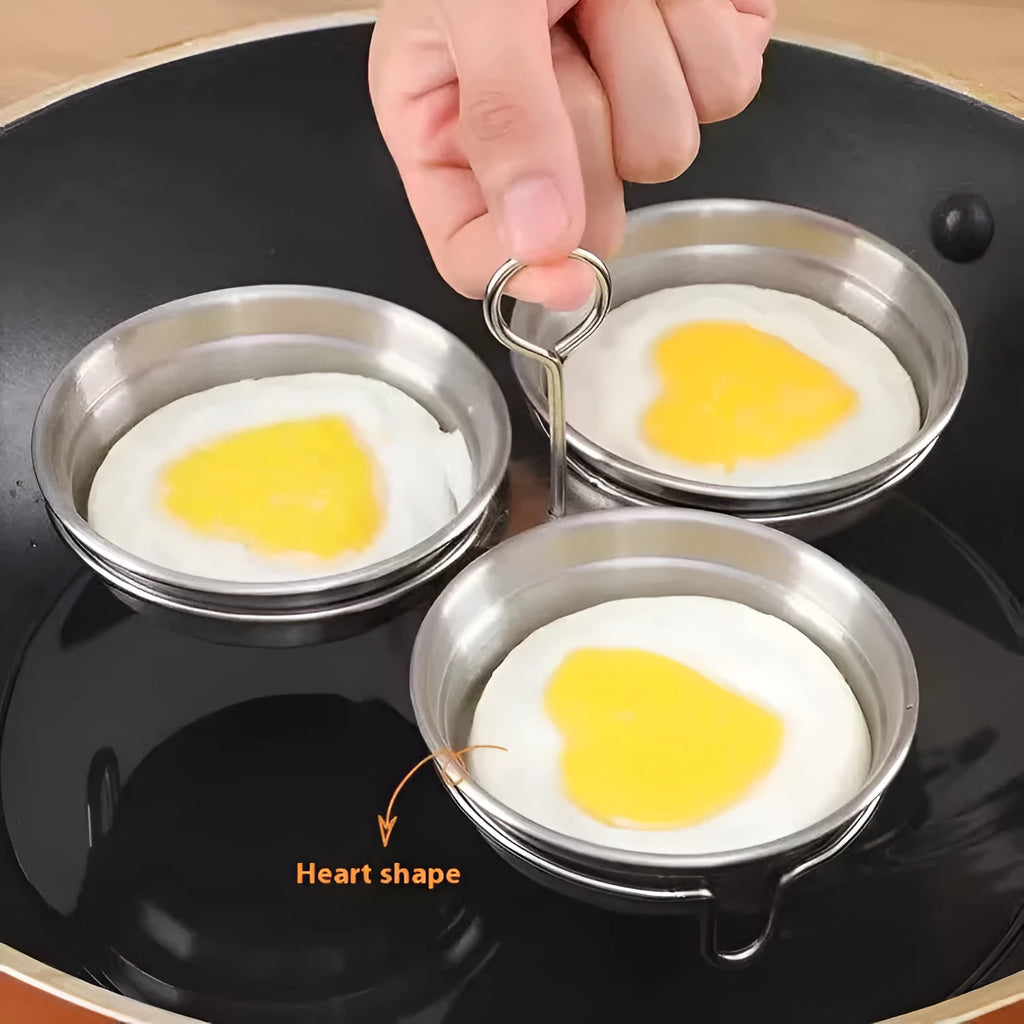 Mini stainless steel heart-shaped egg steamer for cooking soft-boiled or poached eggs on a stove.