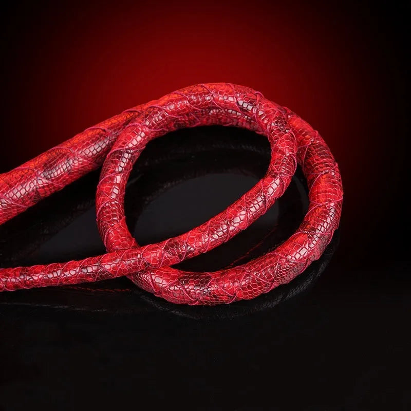 Red PU willow leaf whip for BDSM training and role play, lying on a surface.