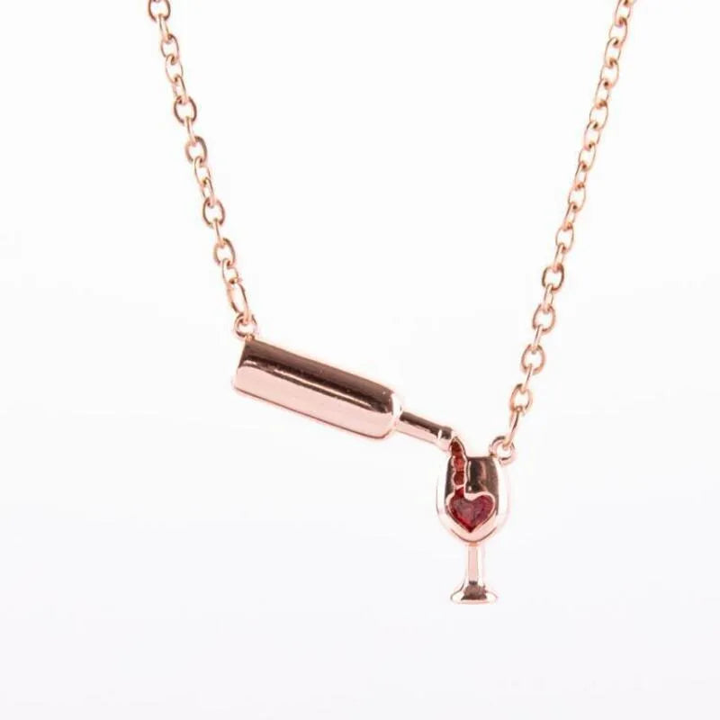 Gold alloy wine bottle and glass pendant necklace on a light background