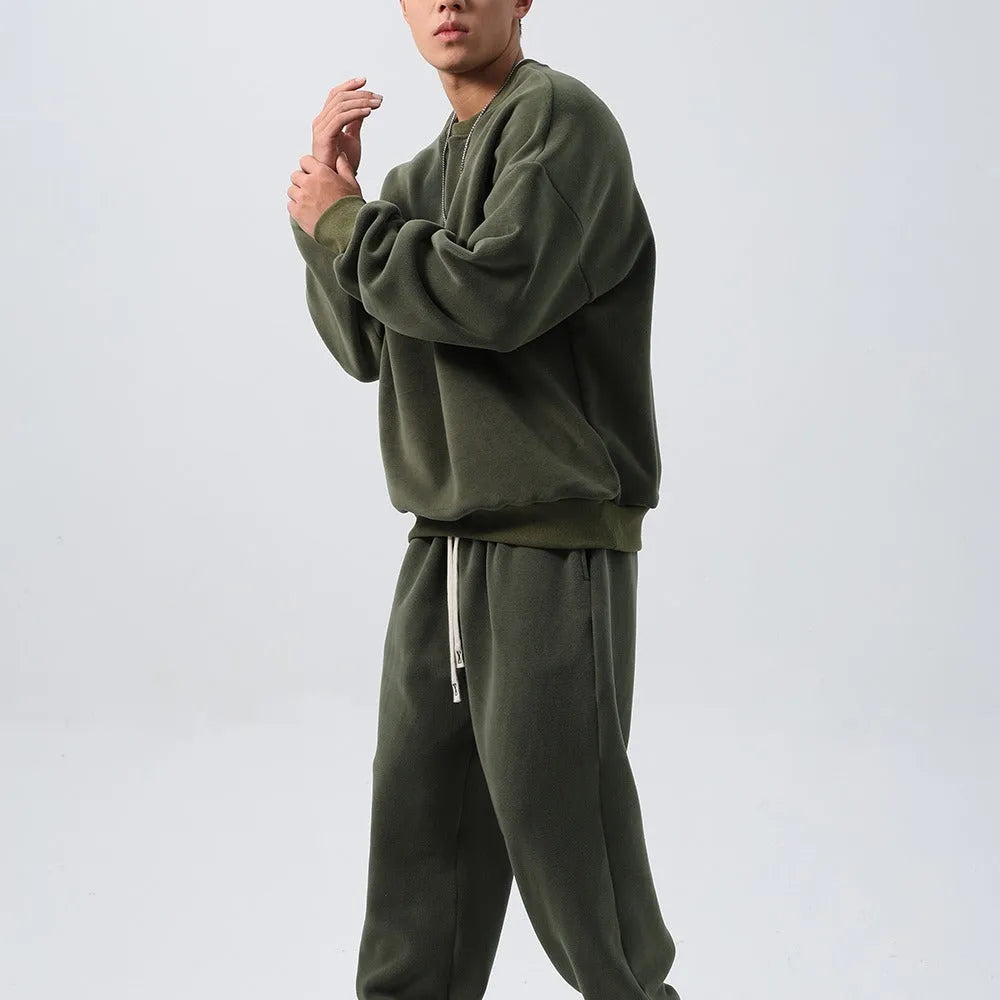 Men's black polar fleece sports suit with crew neck jacket and loose fit trousers laid flat.