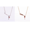 Gold alloy wine bottle and glass pendant necklace on a light background