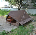 Lightweight brown A-line hiking tent set up with hiking cane supports in outdoor setting