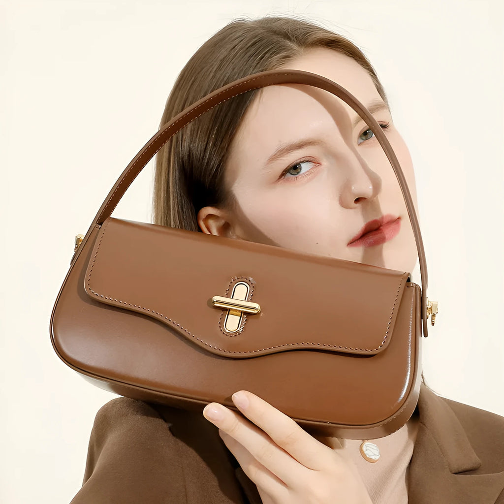 Genuine leather baguette handbag in black with clamshell opening showing internal phone and document pockets