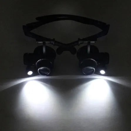 Double eye LED magnifier glasses with headband and 4 interchangeable lenses on black background