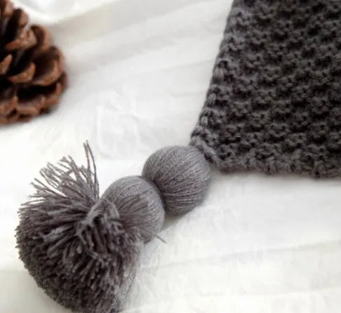 Nordic-style fringed knit acrylic blanket in a neutral colour, shown on a sofa.