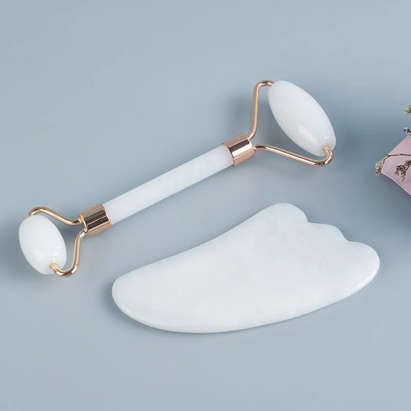 White jade double-headed facial roller and matching gua sha board set on a plain background.