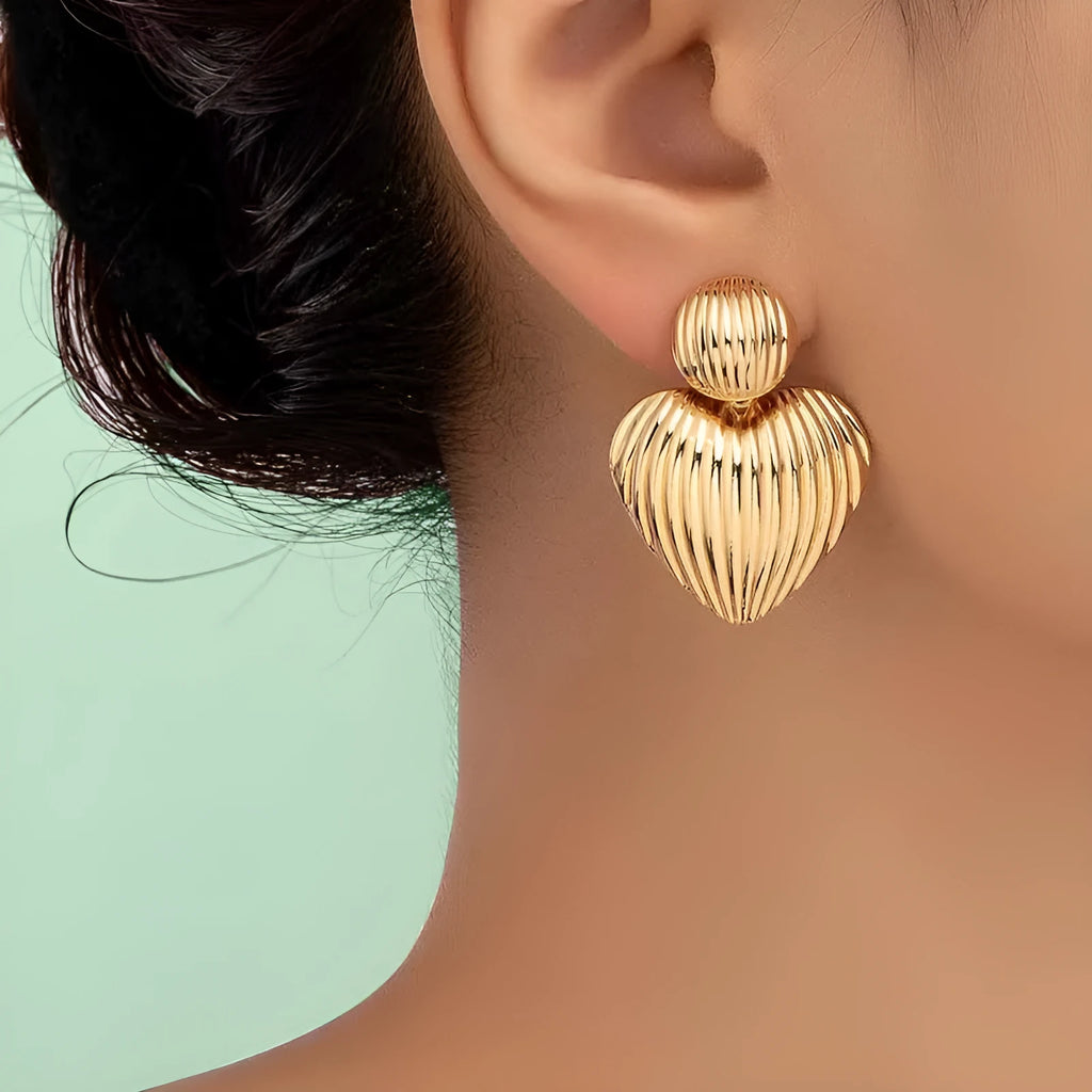 Gold alloy heart-shaped and round earrings for women on a plain background