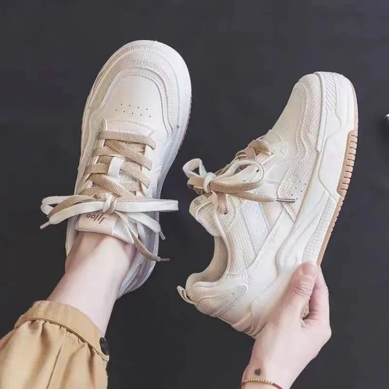 Pink and white low top women's sneakers with a rubber sole and height increasing feature.