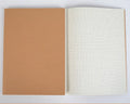 Beige leather thread bound notebook open on a table showing soft paper with ruled lines.