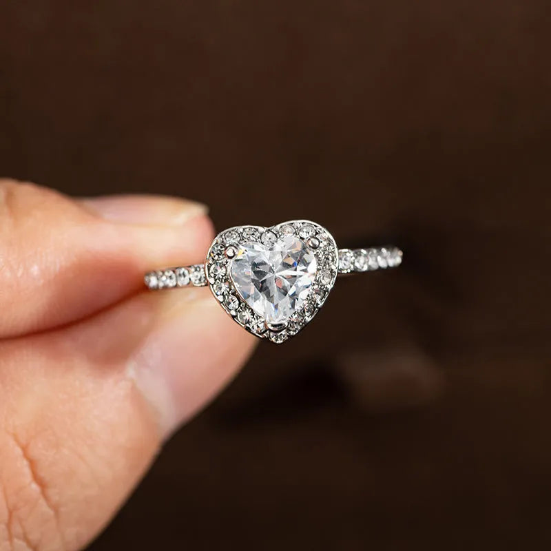Women's heart-shaped wedding ring with central crystal on white copper band in rose gold finish.