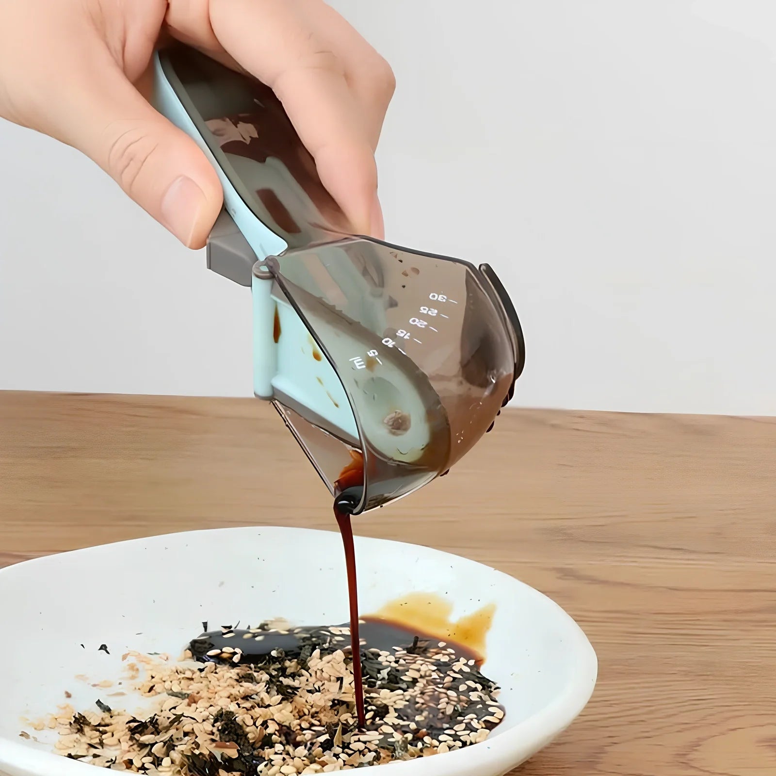 Blue adjustable measuring spoons with magnetic base showing measurement markings from 5ml to 130ml