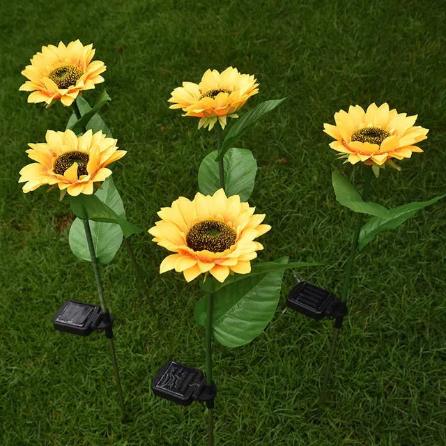 Yellow LED solar sunflower lamp on a lawn with a 66cm stem and 15cm flower head