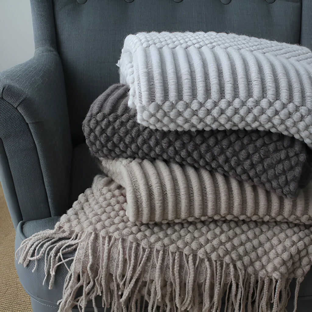 Small light grey polyester fleece throw blanket folded on a sofa.
