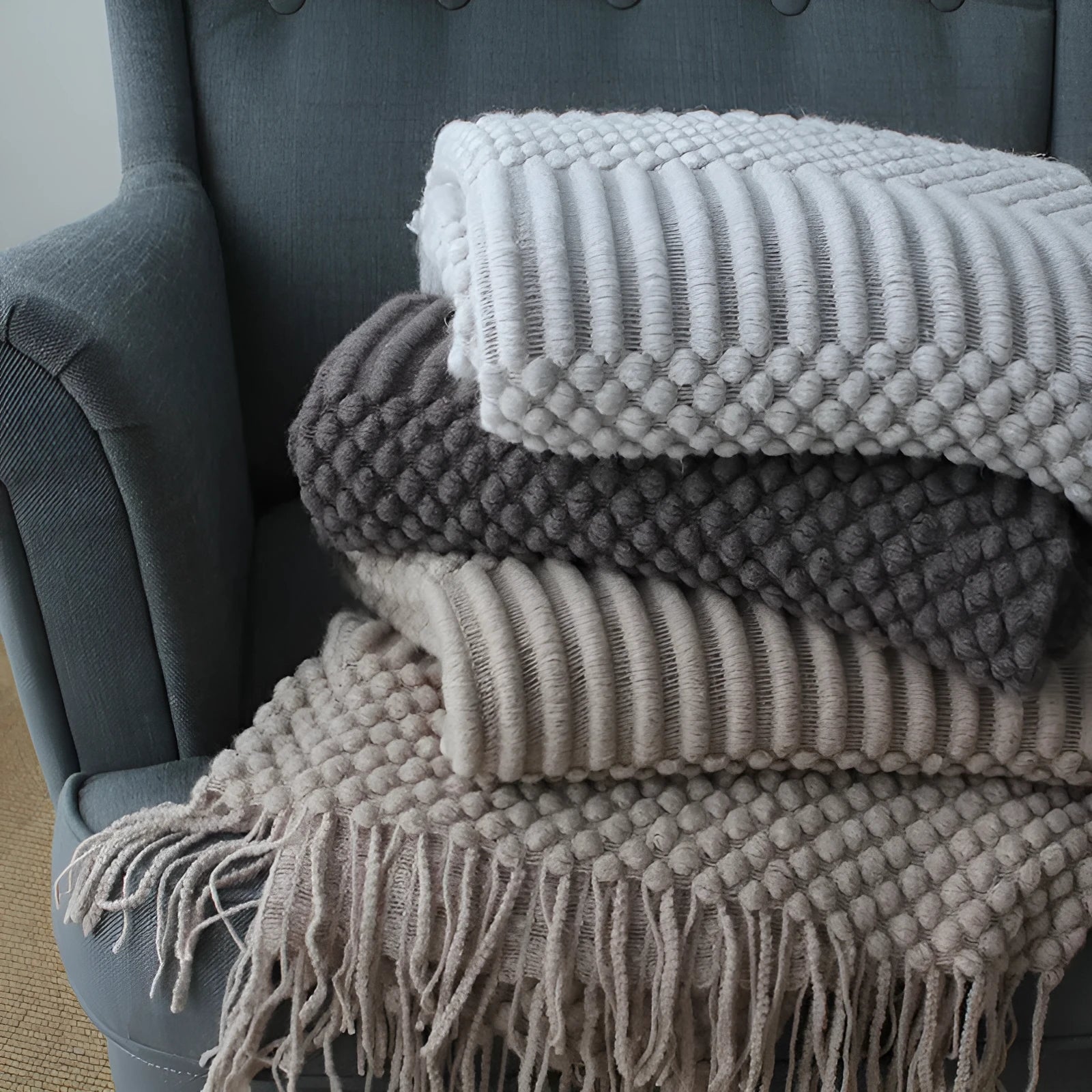 Small light grey polyester fleece throw blanket folded on a sofa.