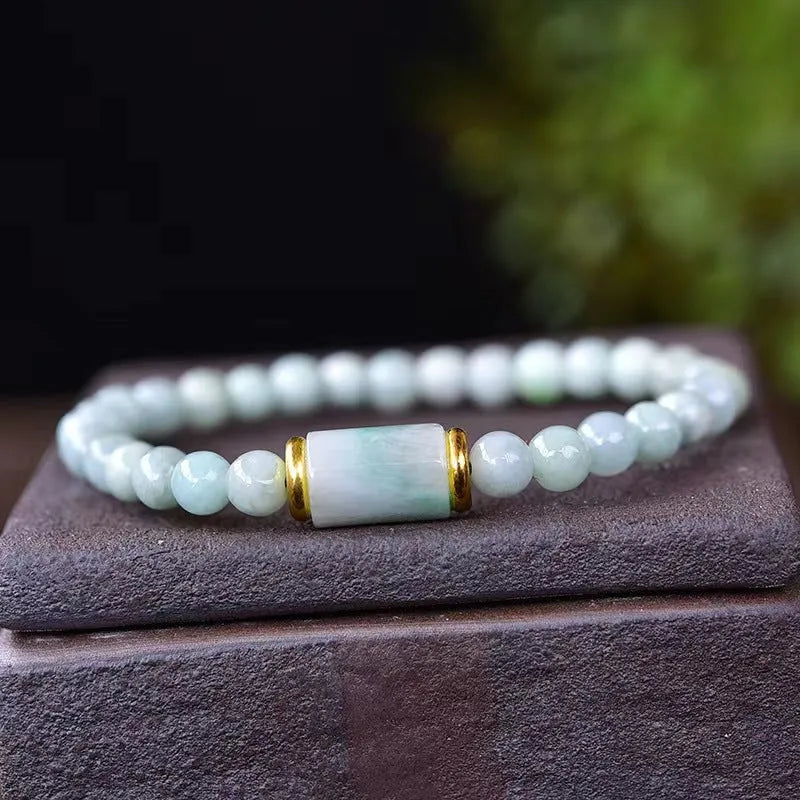 Close-up of a geometric jade bracelet with round emerald-coloured beads on a wrist.