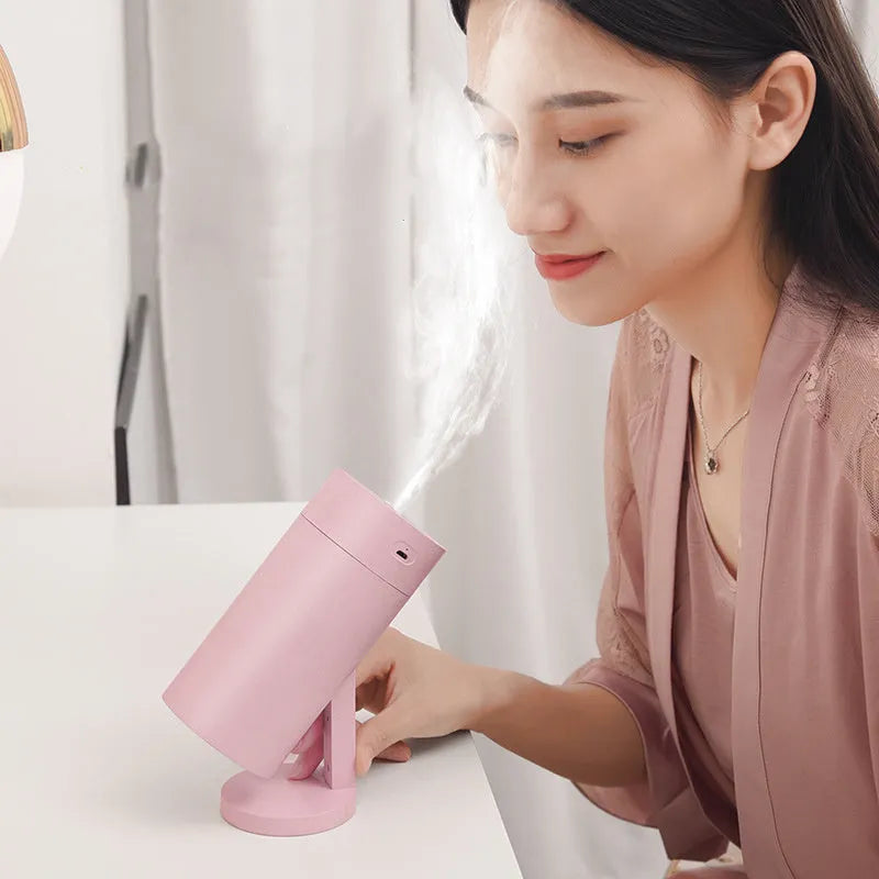 Blue folding bracket USB humidifier on a desk next to a laptop
