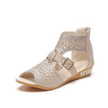 Women's beige patent flat sandals with back zipper and decorative rivets on a low wedge sole.