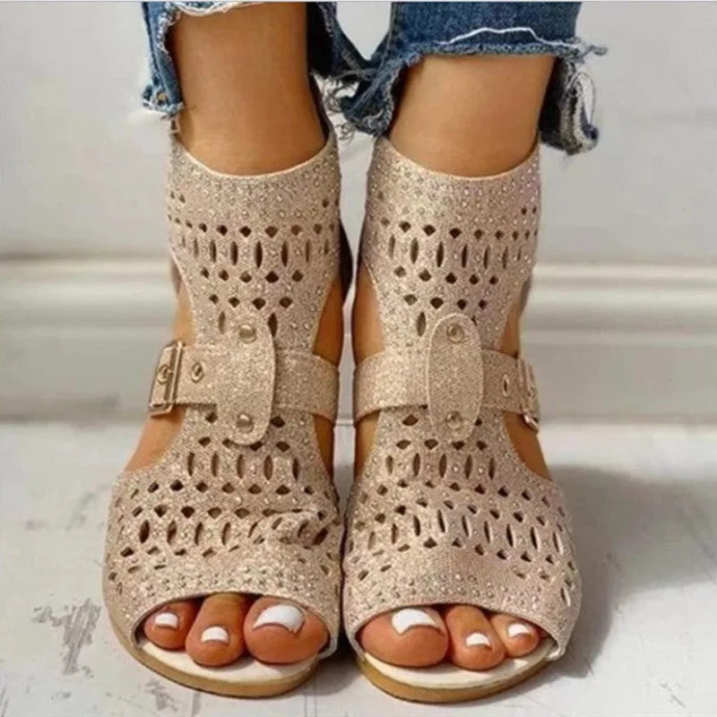 Women's beige patent flat sandals with back zipper and decorative rivets on a low wedge sole.