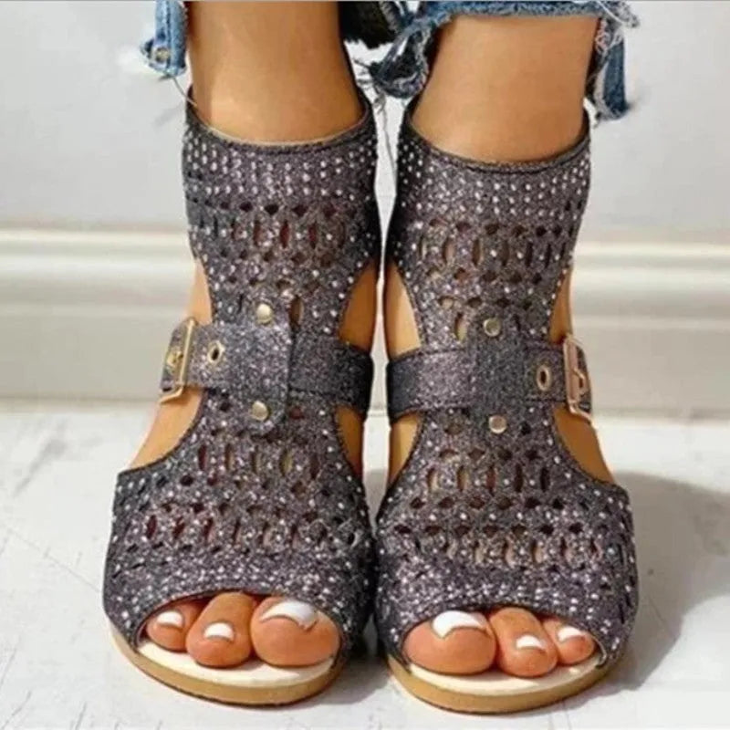 Women's beige patent flat sandals with back zipper and decorative rivets on a low wedge sole.