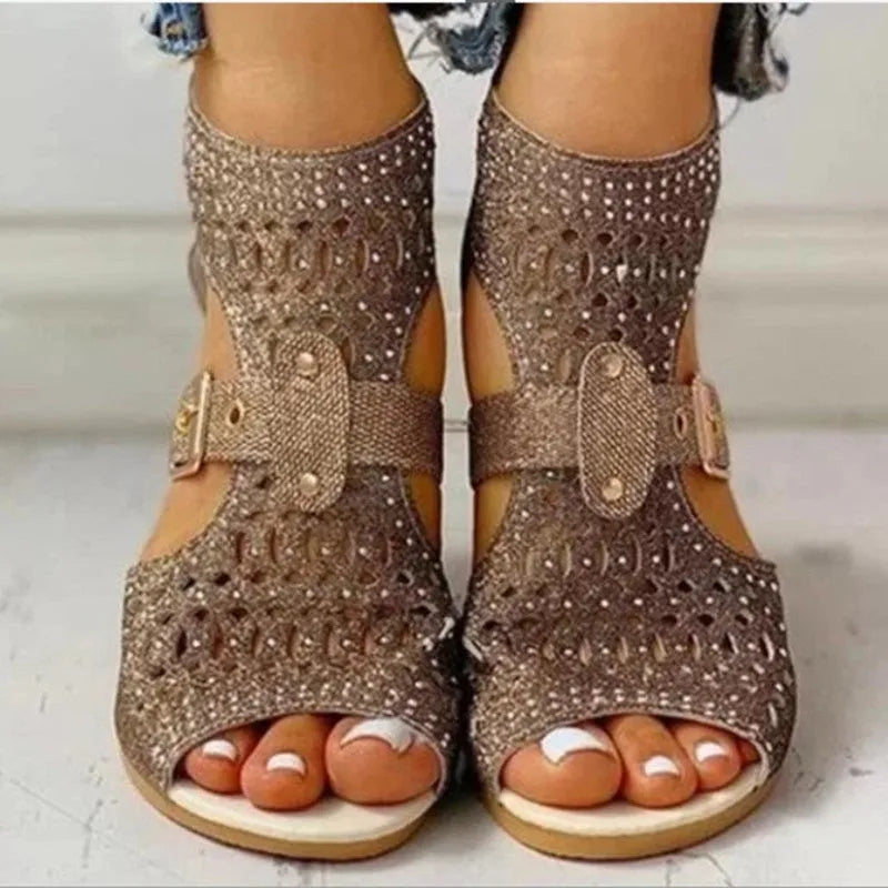 Women's beige patent flat sandals with back zipper and decorative rivets on a low wedge sole.