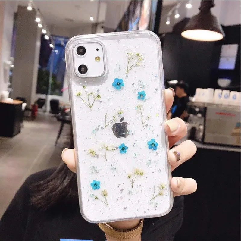Epoxy phone case with real dried flowers and glitter on a TPU back cover, showing a blue floral pattern against a clear resin layer