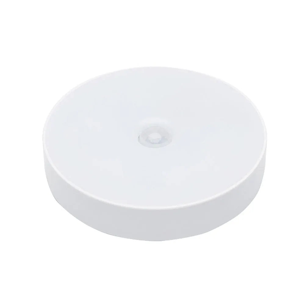 Small, round white LED night light with adhesive backing and a USB charging cable.