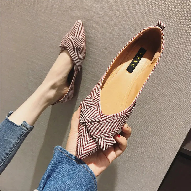 Women's red pointed-toe shallow-mouth flats with a low flat heel on a plain background.
