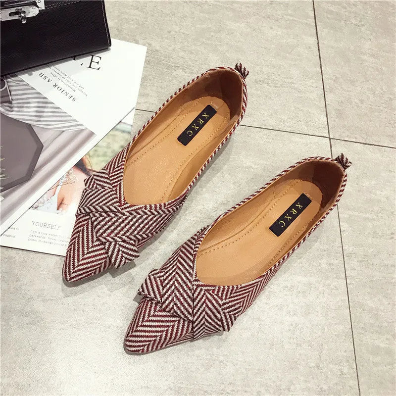 Women's red pointed-toe shallow-mouth flats with a low flat heel on a plain background.