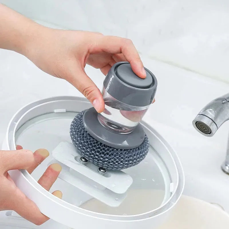 Kitchen cleaning brush with push-button soap dispenser and scrubber head.