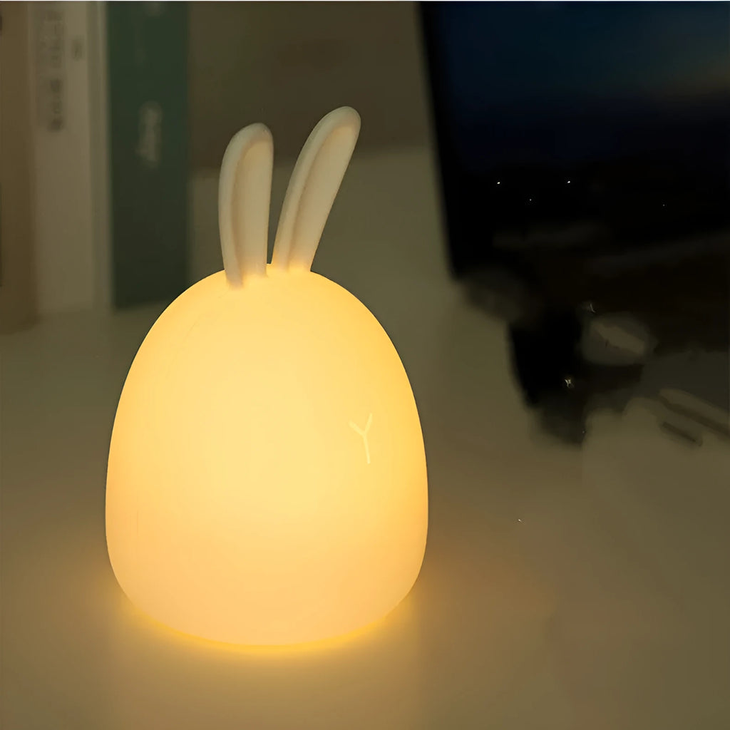 White fat rabbit silicone lamp with touch switch and charging base on a plain background