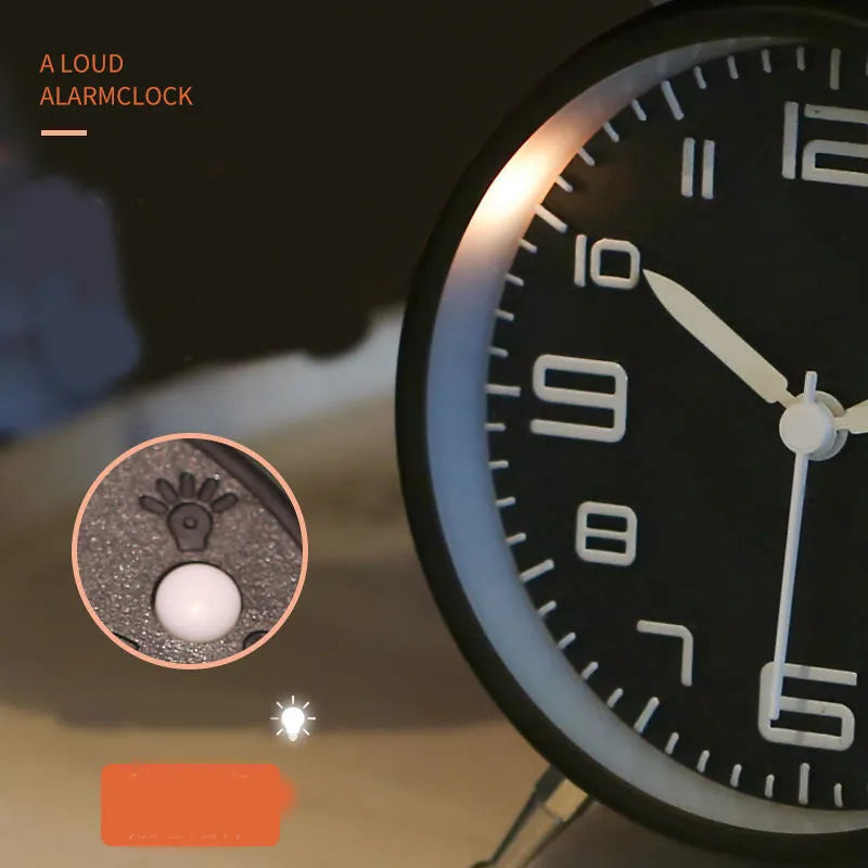 Large black metal alarm clock with luminous hands and face, 4 inches, on a wooden bedside table