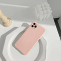 Simple solid colour silicone iPhone case in blue, pink, and white on a table