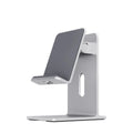 Dark grey alloy mobile phone and tablet holder with adjustable clamp on a wooden desk.