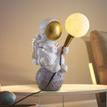 White astronaut figure children's desk lamp and night light in seated, standing, or wall lamp styles.
