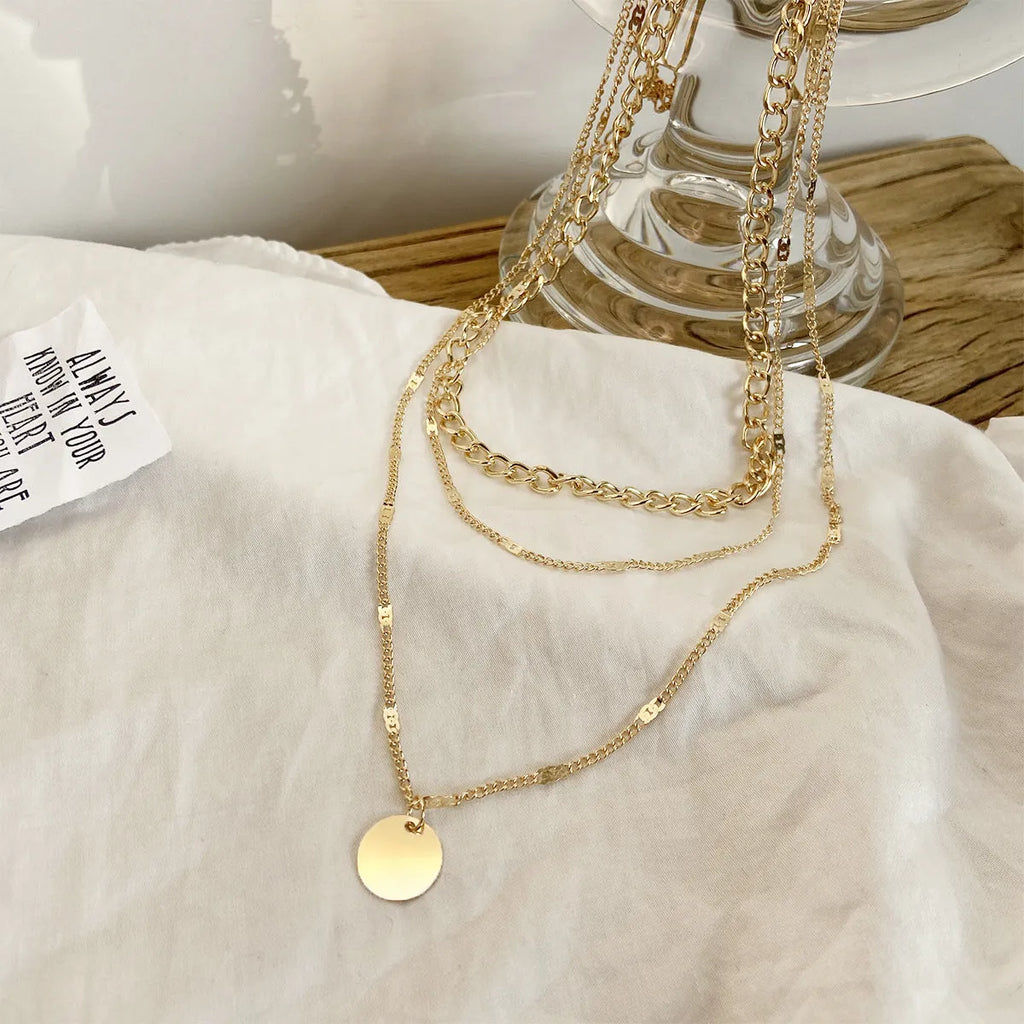 Women's multilayer disc pendant clavicle necklace in gold and silver colour finish on a light background